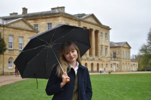 Photo of author Katie Kennedy standing in front of a historical building under an umbrella